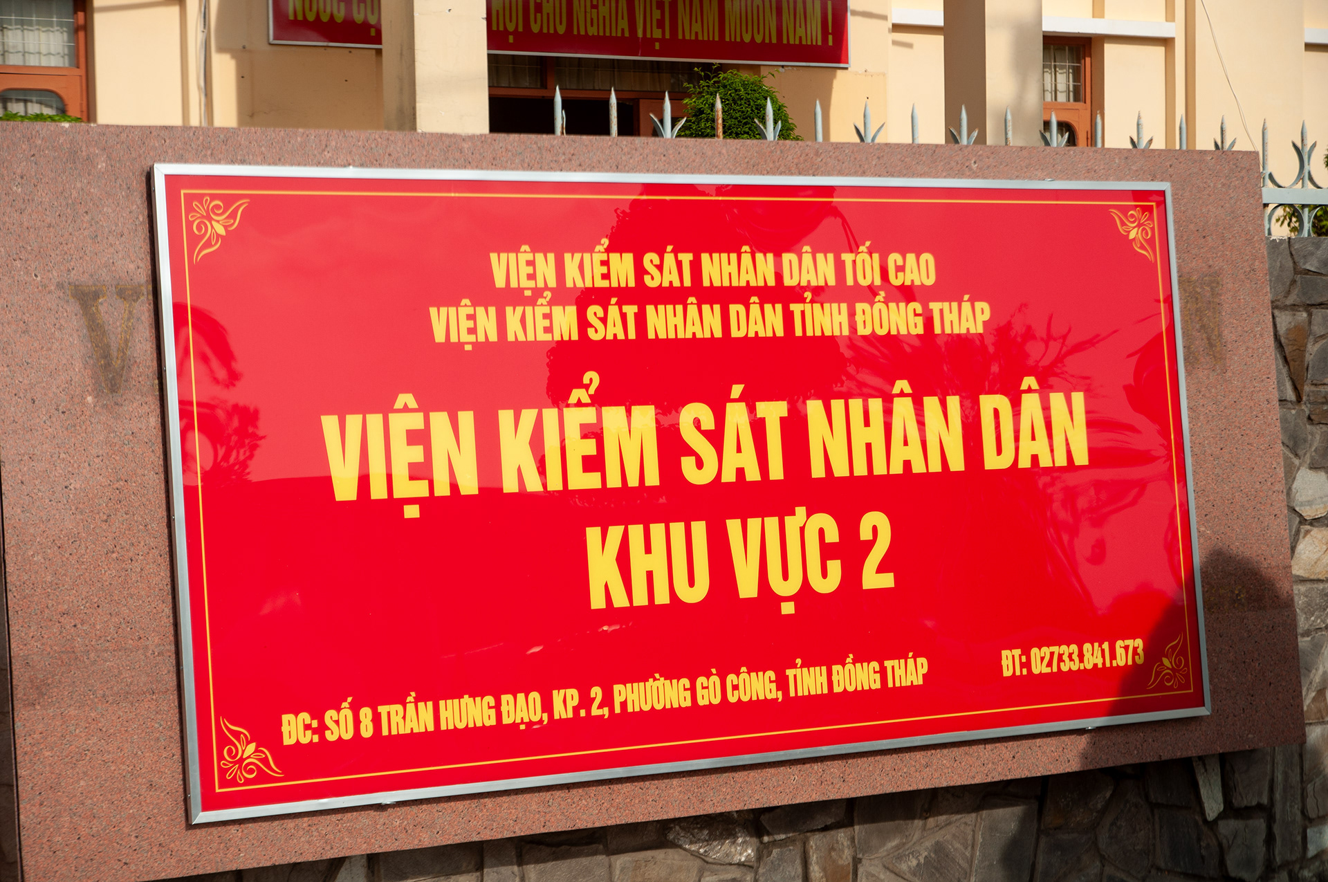 Biển hiệu Viện Kiểm sát Nhân dân Khu vực 2 tỉnh Đồng Tháp bằng Alu đỏ chữ nổi màu vàng, lắp đặt cố định trên bức tường đá granite bên ngoài trụ sở.