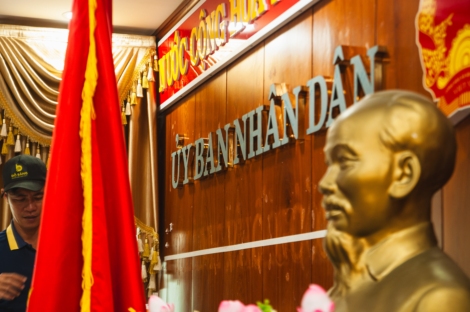 Chữ nổi Ủy ban Nhân dân bằng inox gương vàng trên vách gỗ hội trường khánh tiết.