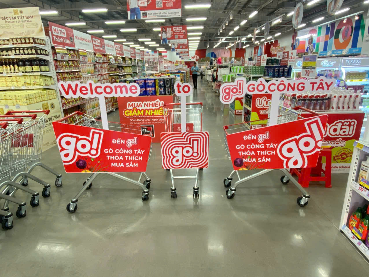 Hệ thống xe đẩy siêu thị GO! Gò Công Tây được gắn biển quảng cáo POSM đồng bộ màu đỏ bắt mắt bên trong khu vực quầy kệ trưng bày hàng hóa.