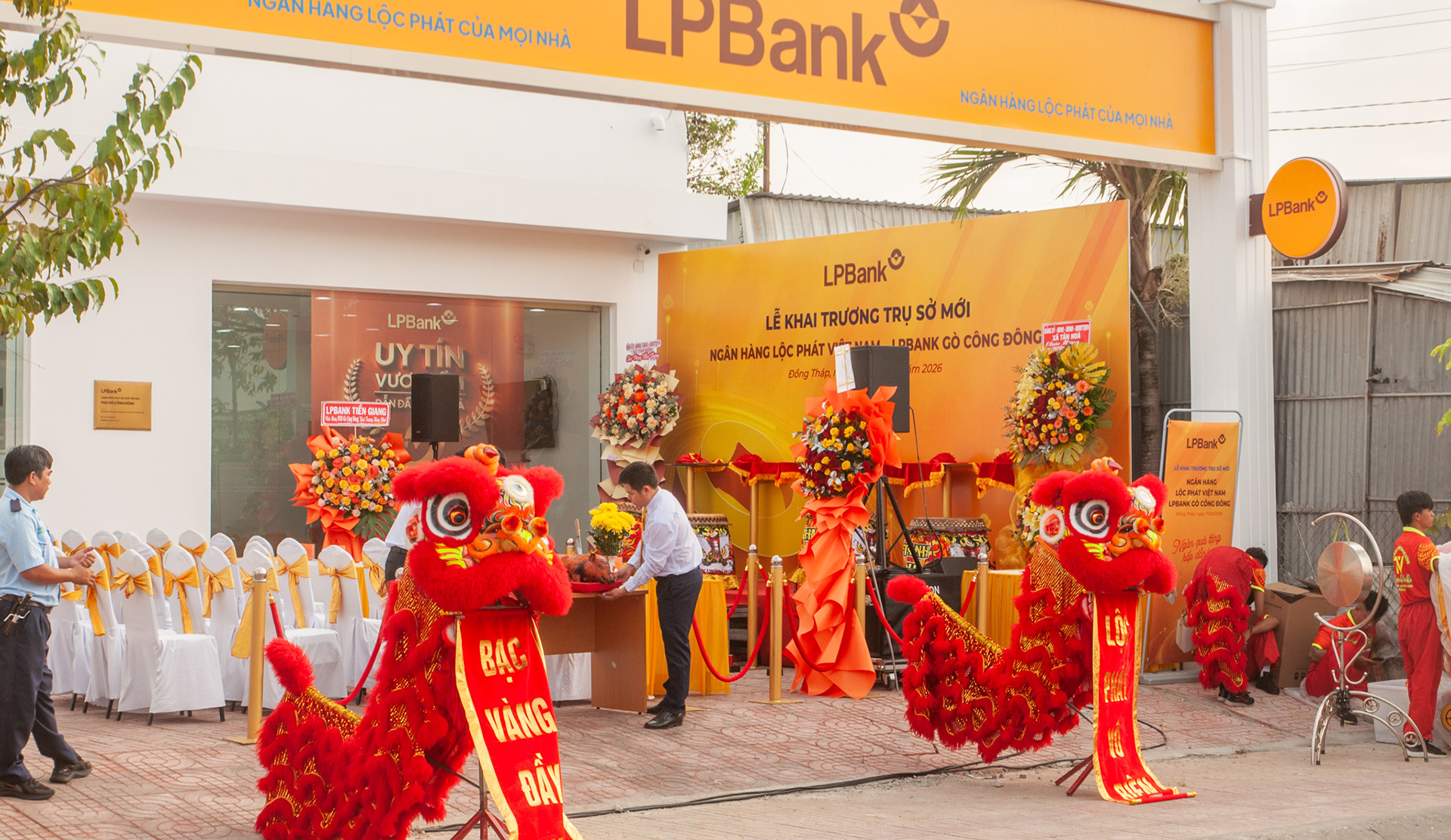 Quang cảnh chuẩn bị cho lễ khai trương LPBank Gò Công Đông với đội múa lân đỏ và bàn cúng lễ trước sân khấu.